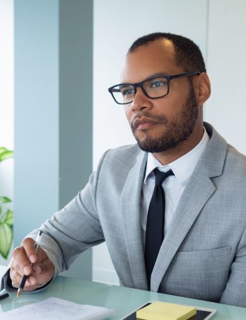 Focused business professional listening to speaker during meeting or conference. Businessman sitting at meeting table in boardroom and looking away. Conference concept